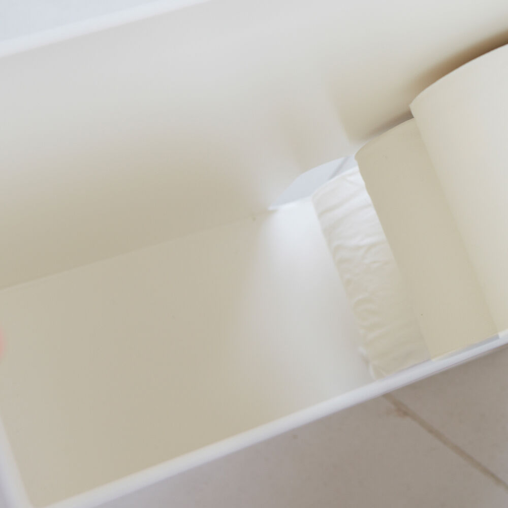 Vorderansicht des weißen Toilettenpapierständers von Yamazaki Home mit Toilettenpapier und Dekorationsartikeln im Badezimmer.